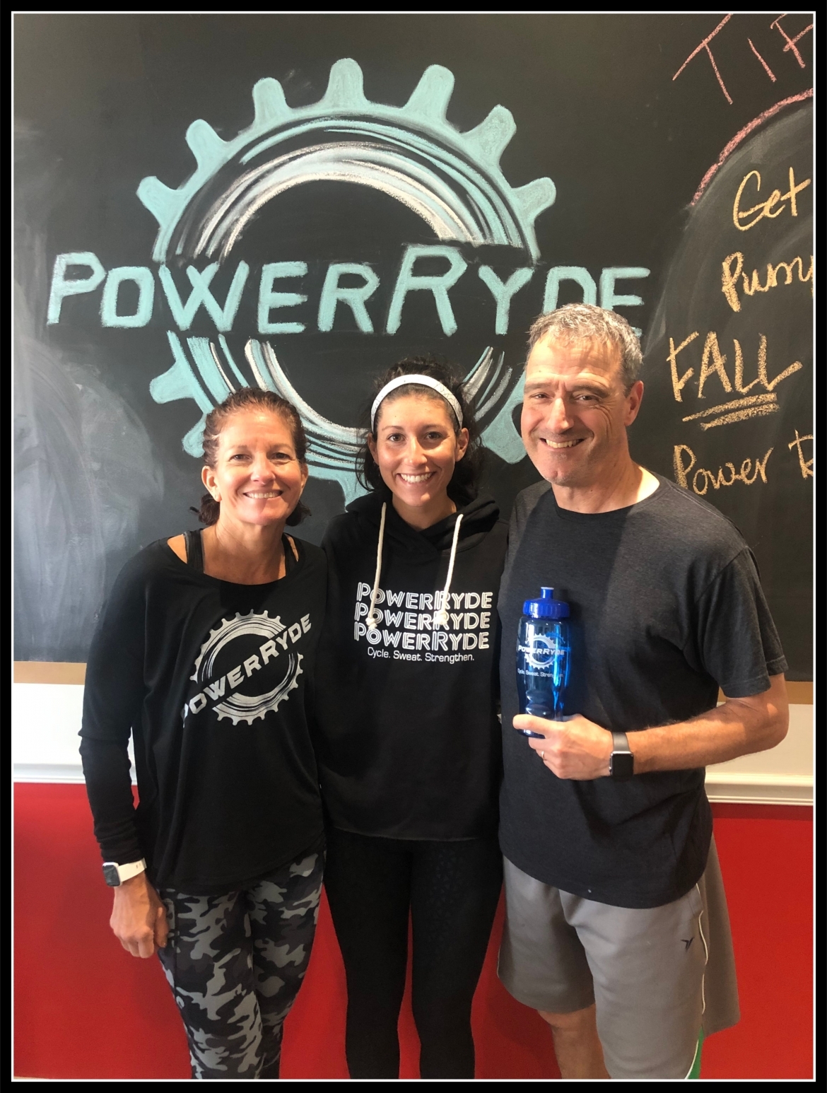 group smiling for photo in front of PowerRyde chalk logo